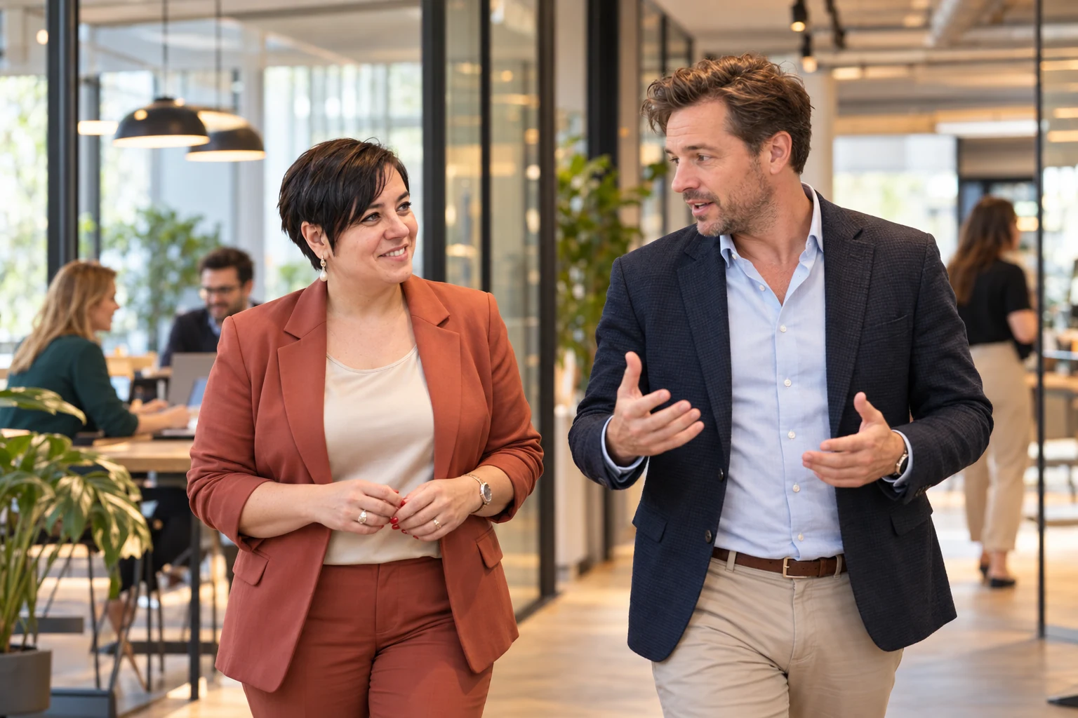 An Vermeulen wandelt in gesprek met een ondernemer door een bedrijfsomgeving.
