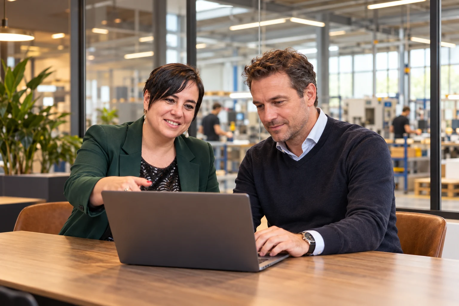 An Vermeulen overlegt met een ondernemer bij een laptop in een bedrijfsomgeving.