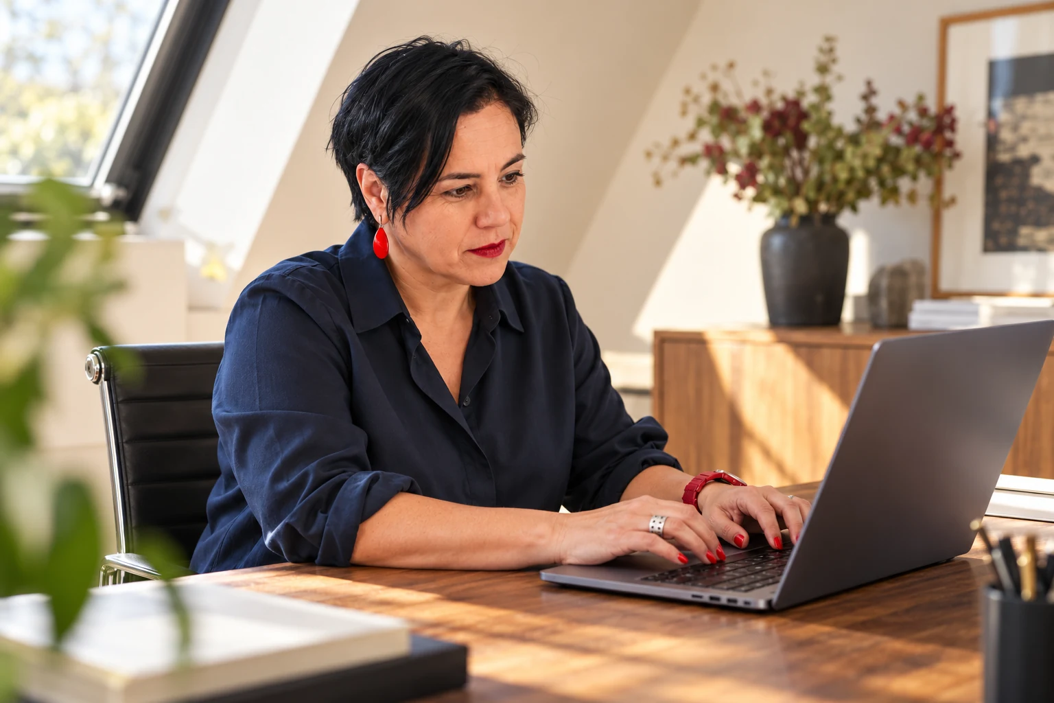 An Vermeulen in een donkerblauwe blouse werkt geconcentreerd aan een laptop.