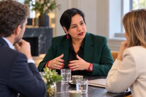 An Vermeulen in een groene blazer bespreekt een punt met twee gesprekspartners aan tafel.